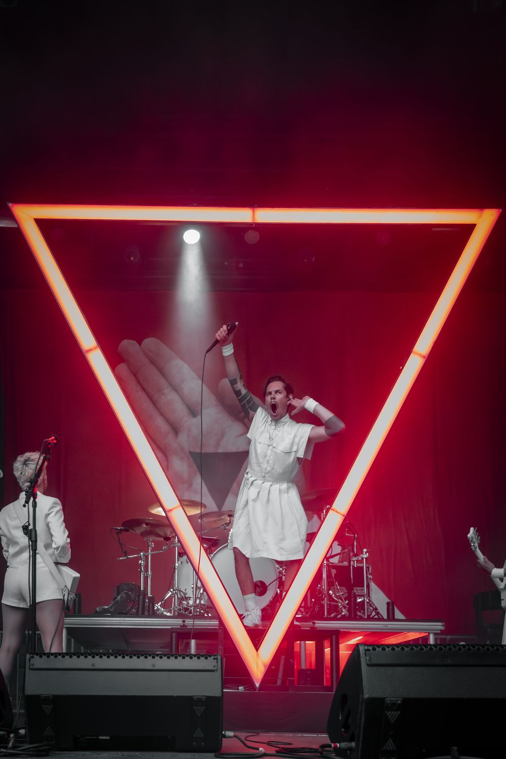 Concert Cachemire, chanteur sur scène dans un décor triangulaire néon rouge
